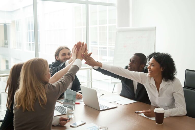 colleagues high fiving during a work meeting